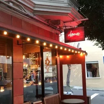 Domo restaurant storefront at dusk with neon signage and string lighting