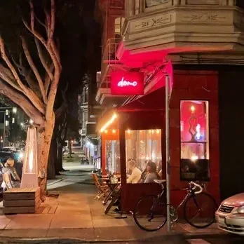 Nighttime exterior shot with red neon signage and warm sidewalk lighting