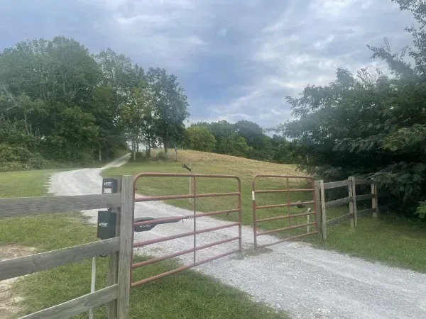 Gravel driveway and open metal gates leading to rural property in Lewisburg, TN