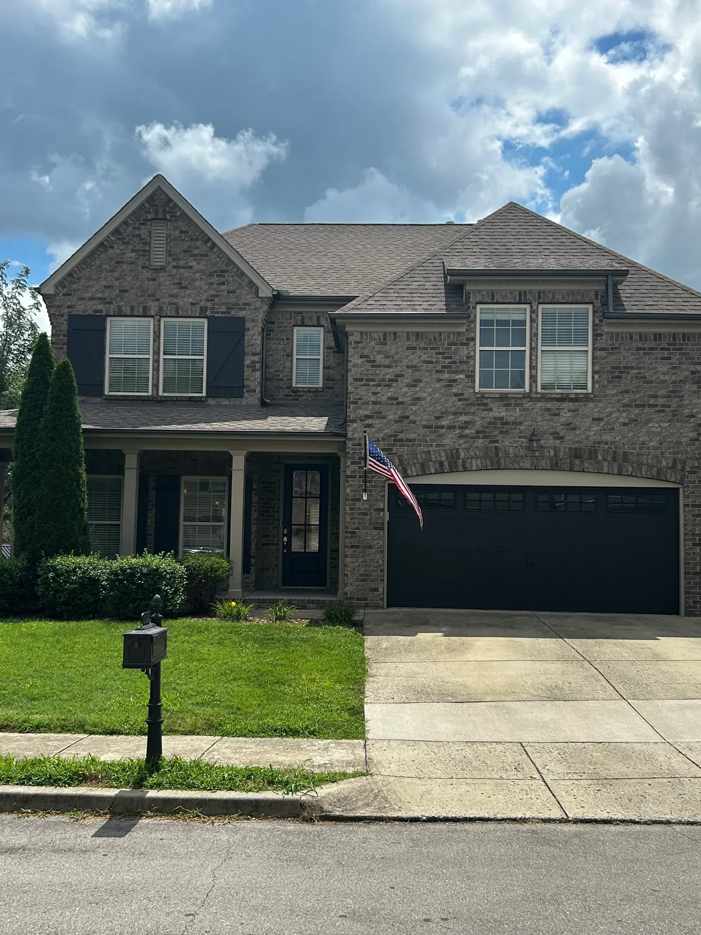 Traditional brick home facade with multi-gabled roofline and dark shutters in Thompson's Station, TN
