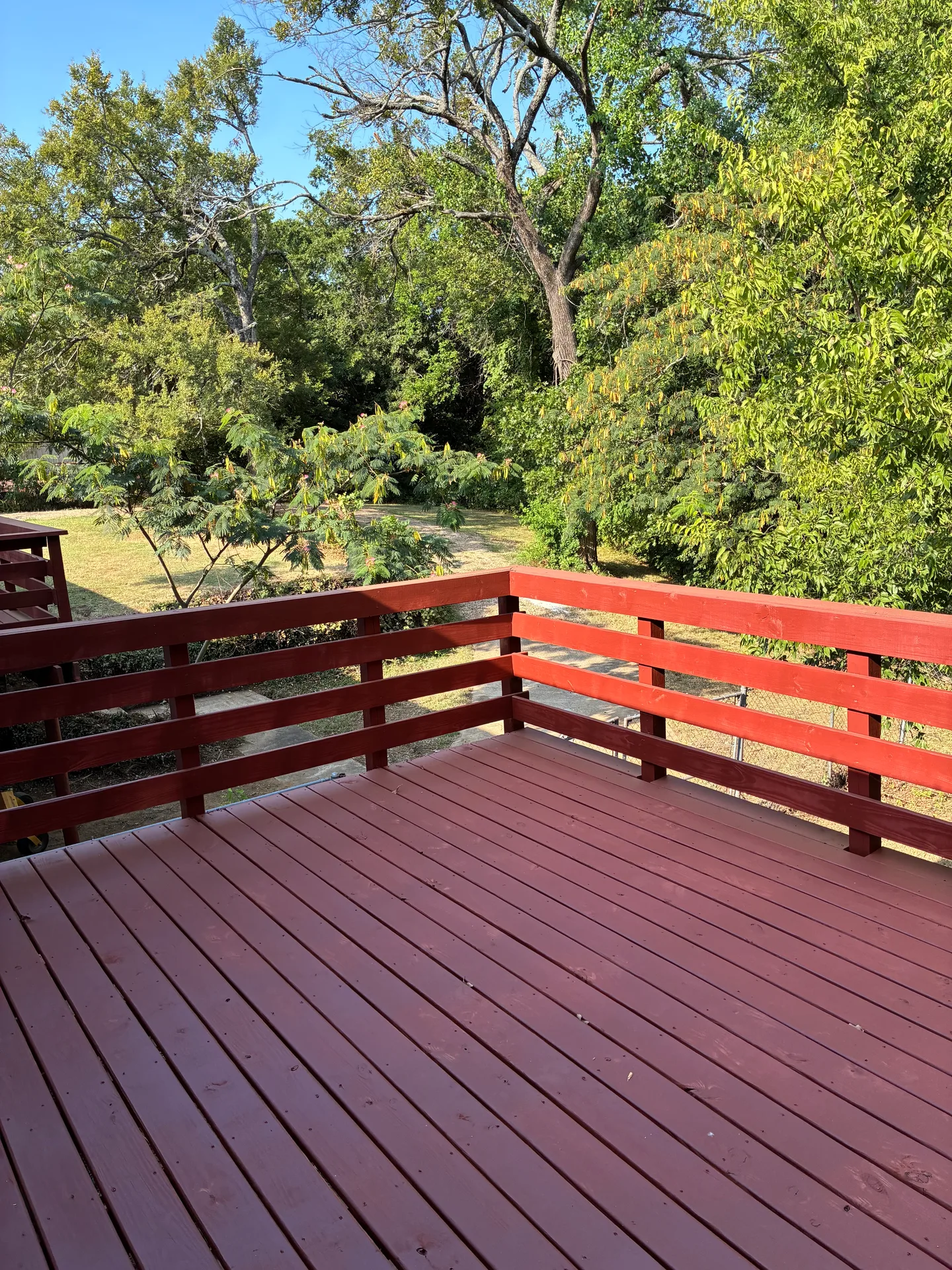 Elevated wooden deck with red railings overlooking a canopy of mature trees