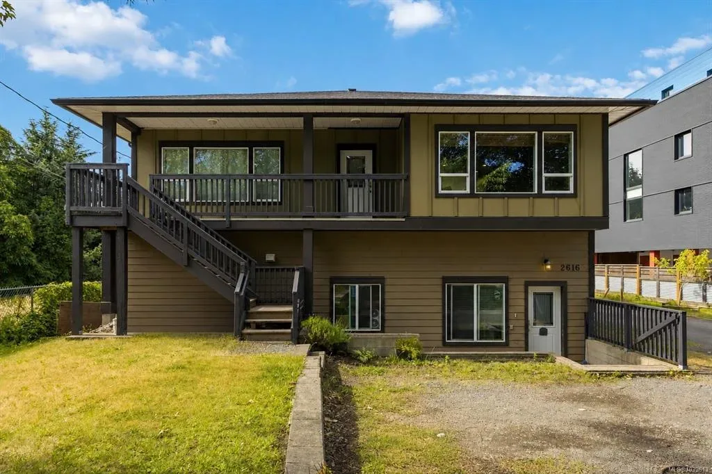 Front exterior facade of 2616 Sooke Road, a two-storey home with green siding and dark wood trim