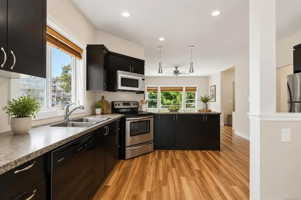 Main-floor kitchen with dark espresso cabinetry, stainless steel appliances, and pendant lighting