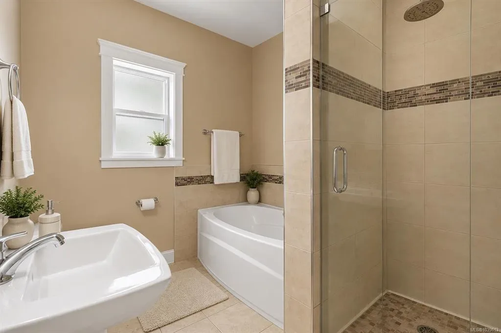 Main-floor bathroom with pedestal sink, soaking tub, and glass walk-in shower