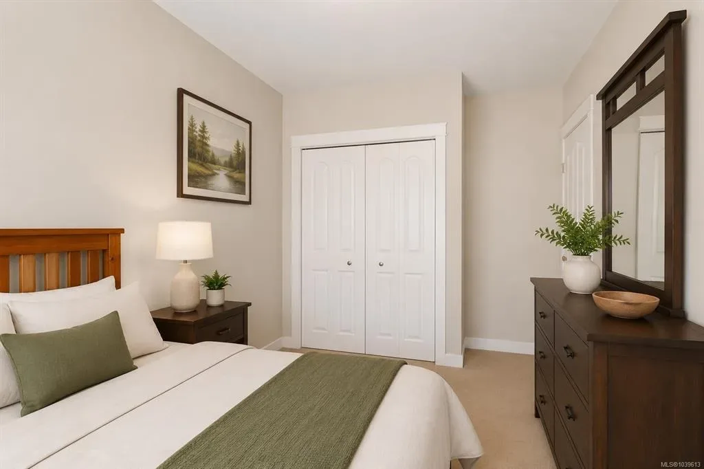 Secondary bedroom with neutral walls, carpet, and wood-toned furniture