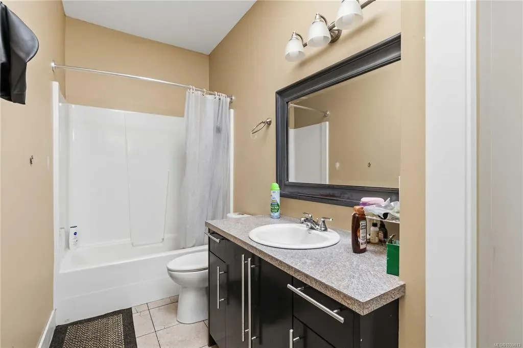 Bathroom with dark espresso vanity, framed mirror, and tub-shower combination