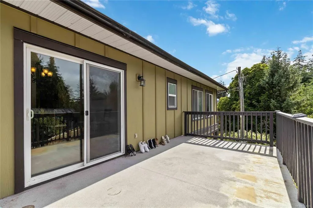 Deck off the main living area with olive green siding, dark railings, and treetop views