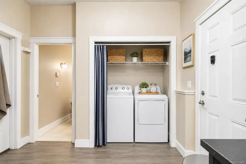 Legal-suite laundry closet with stacked washer and dryer and staged decor