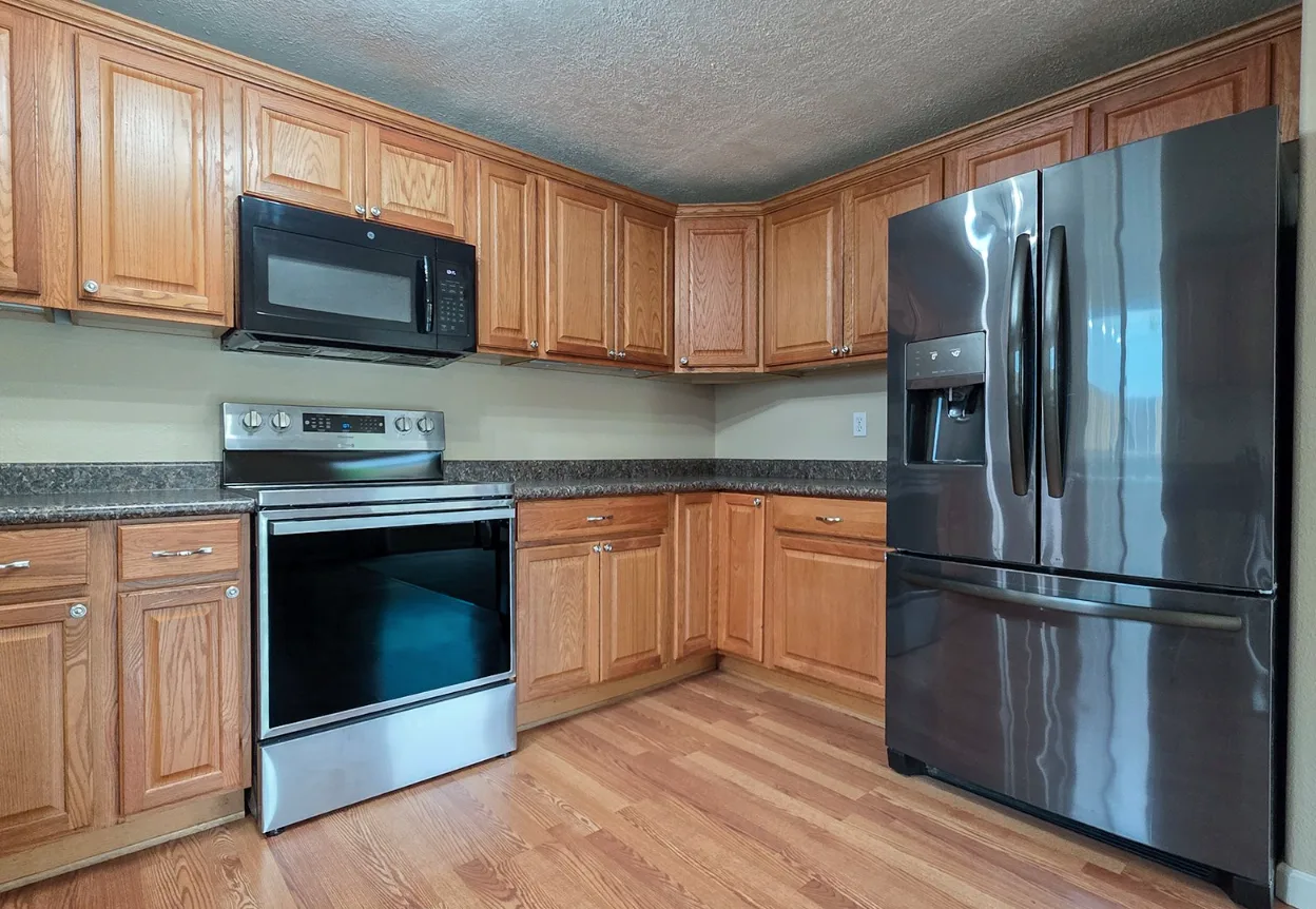 Kitchen with natural oak cabinetry, stainless steel appliances, and laminate countertops