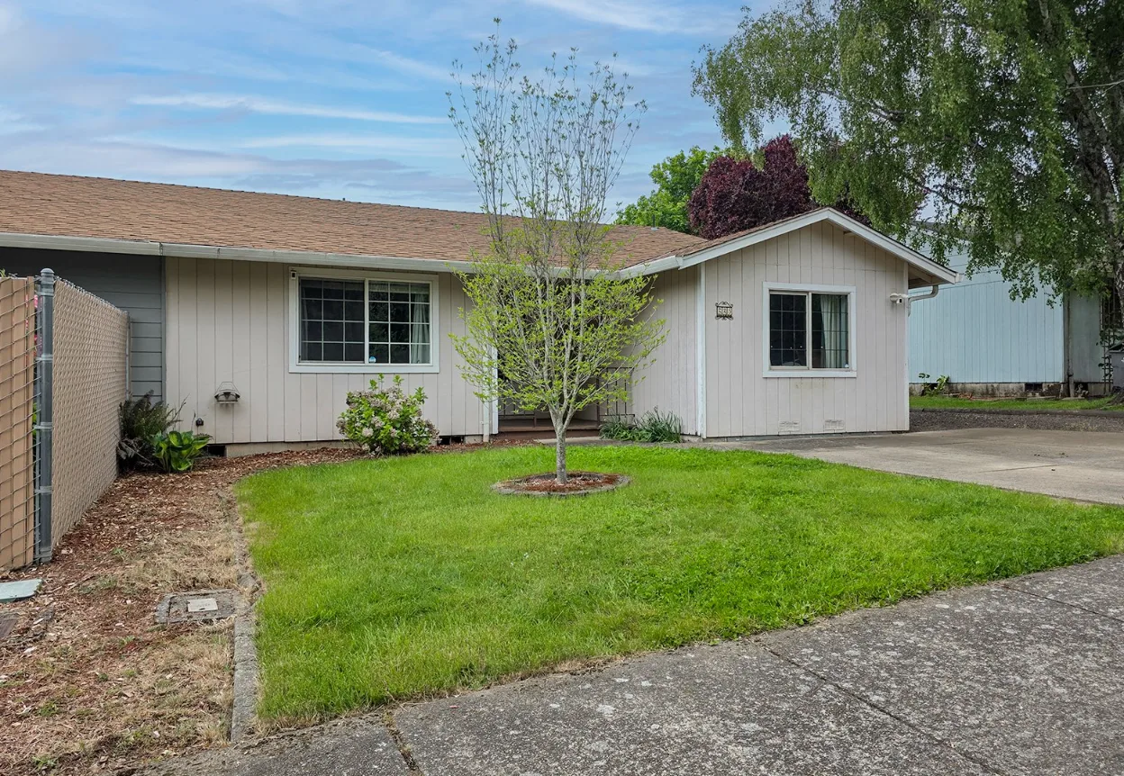 225 SW Fleishauer Ln - front facade with chain-link fence and young tree