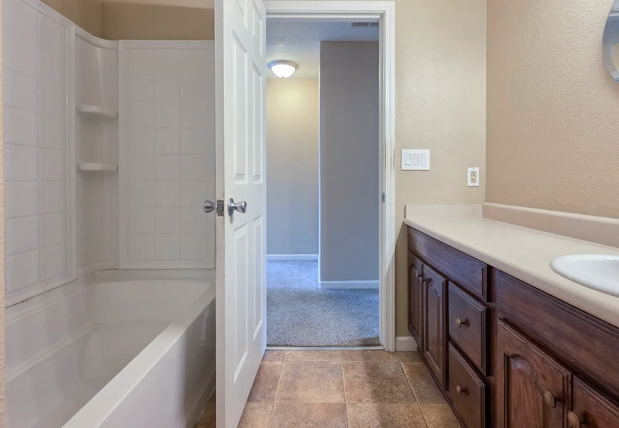 Bathroom with white tub, dark wood vanity, and tile flooring