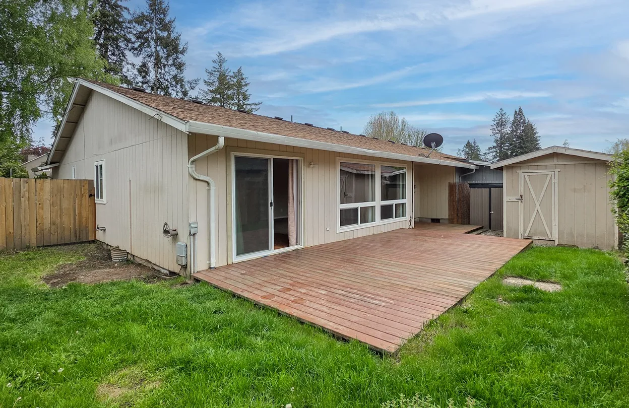 Rear exterior with wooden deck, shed, and privacy fence
