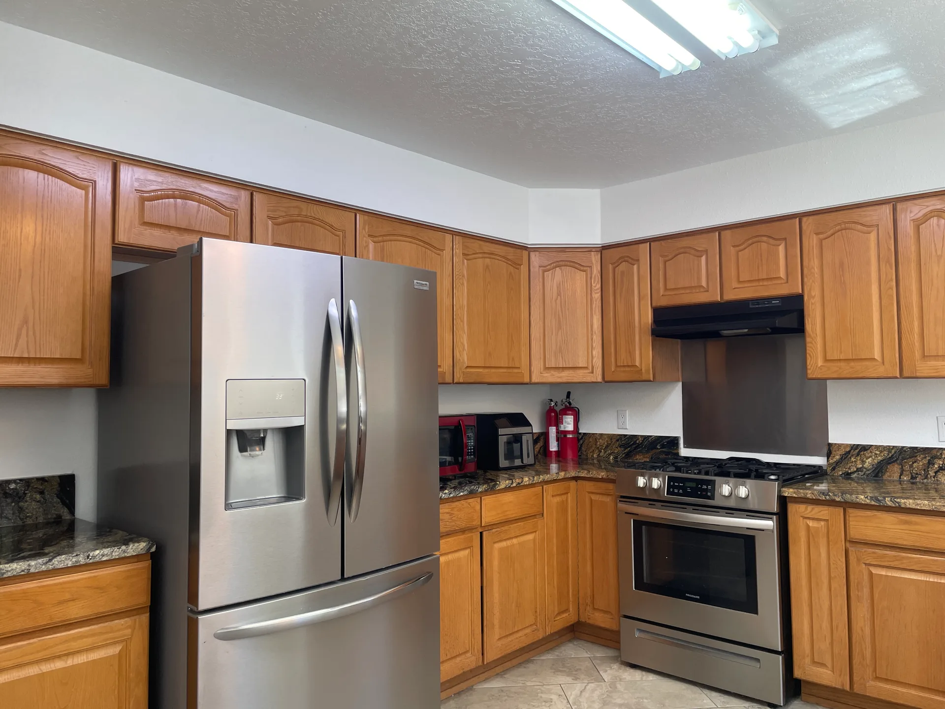 Kitchen with oak cabinetry, dark granite countertops, and stainless steel appliances