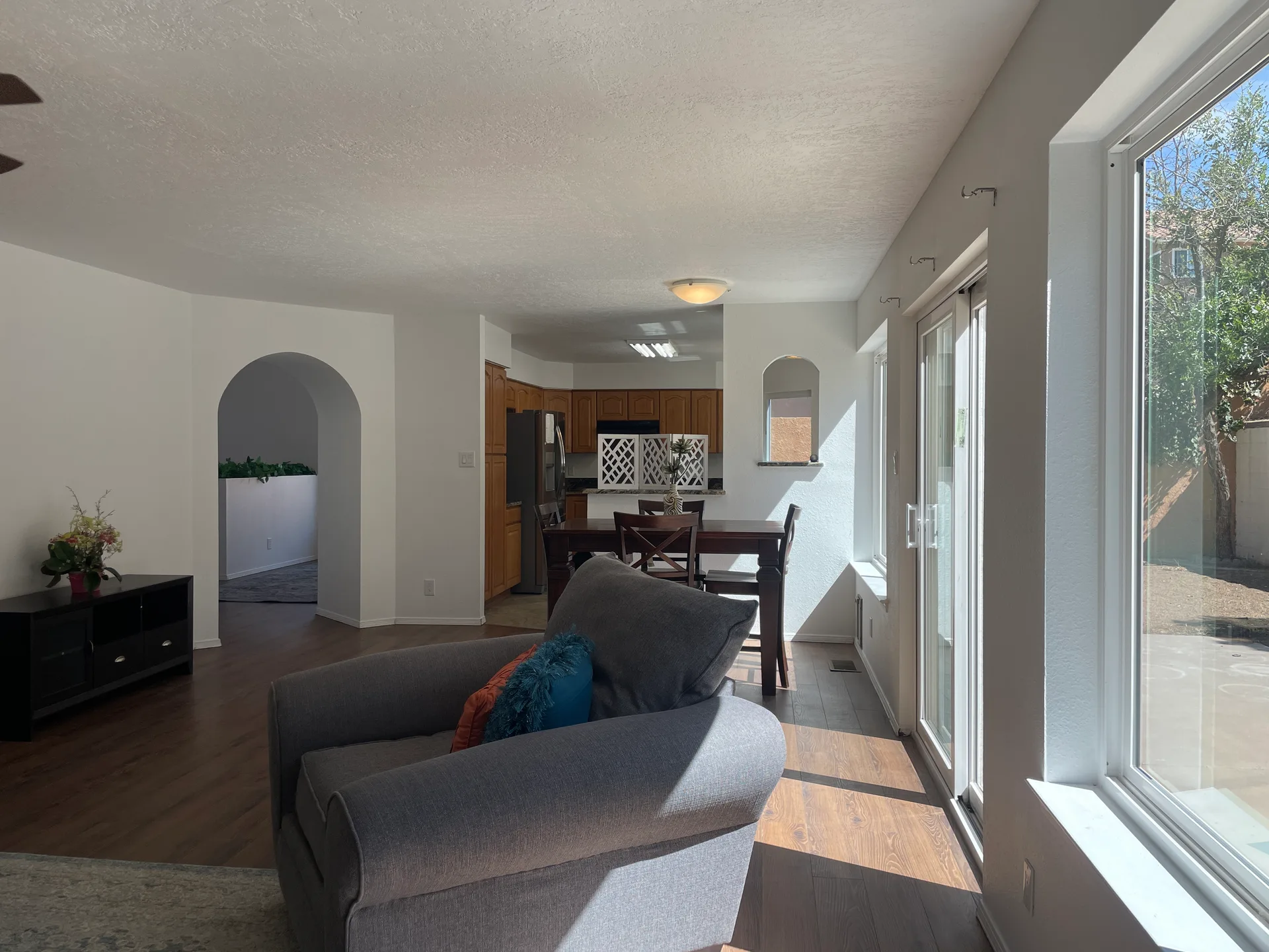 Open-concept living and dining area with wood-look flooring and an arched entry