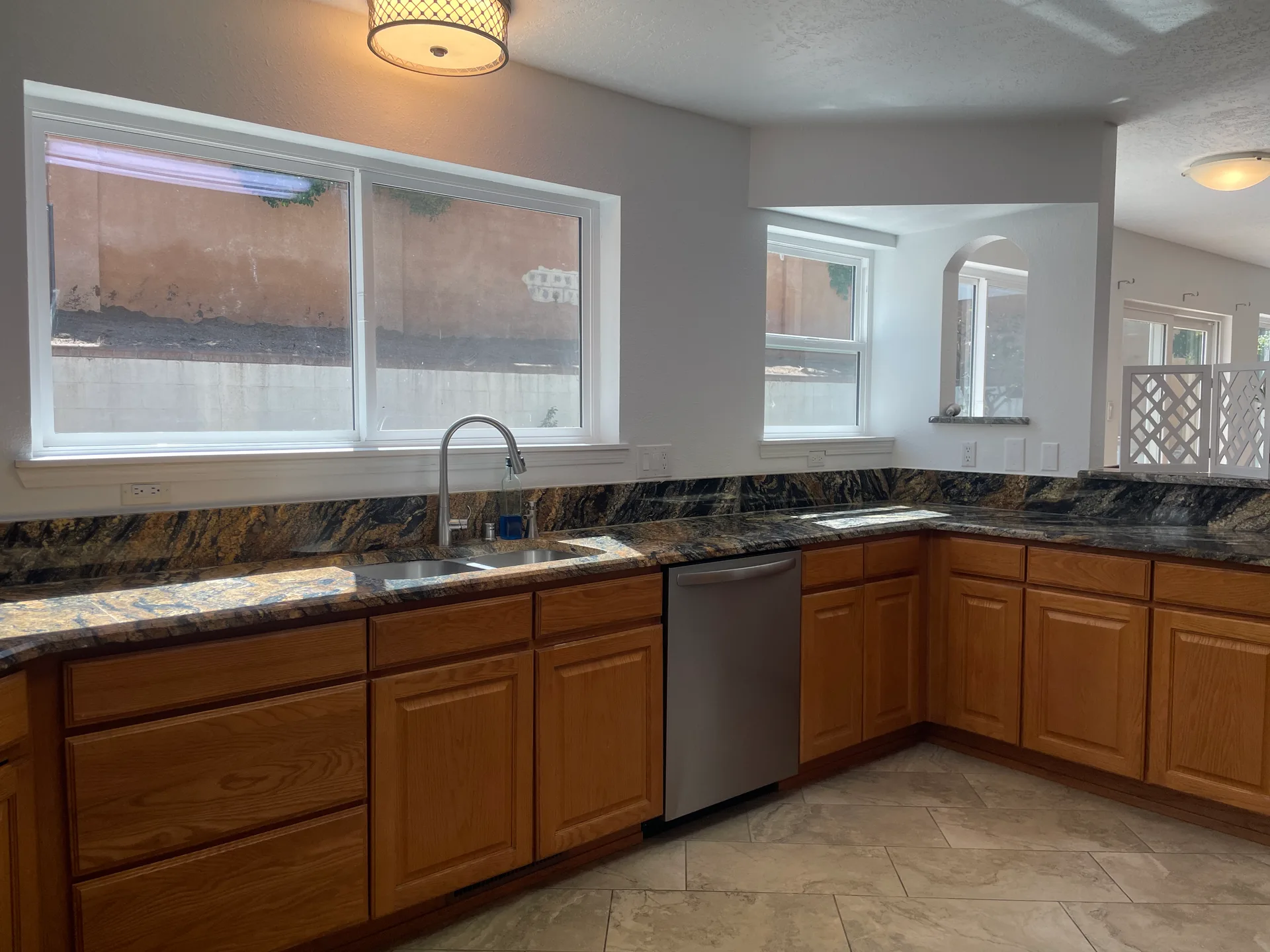 Kitchen sink and counter area with oak cabinetry and dark veined granite counters
