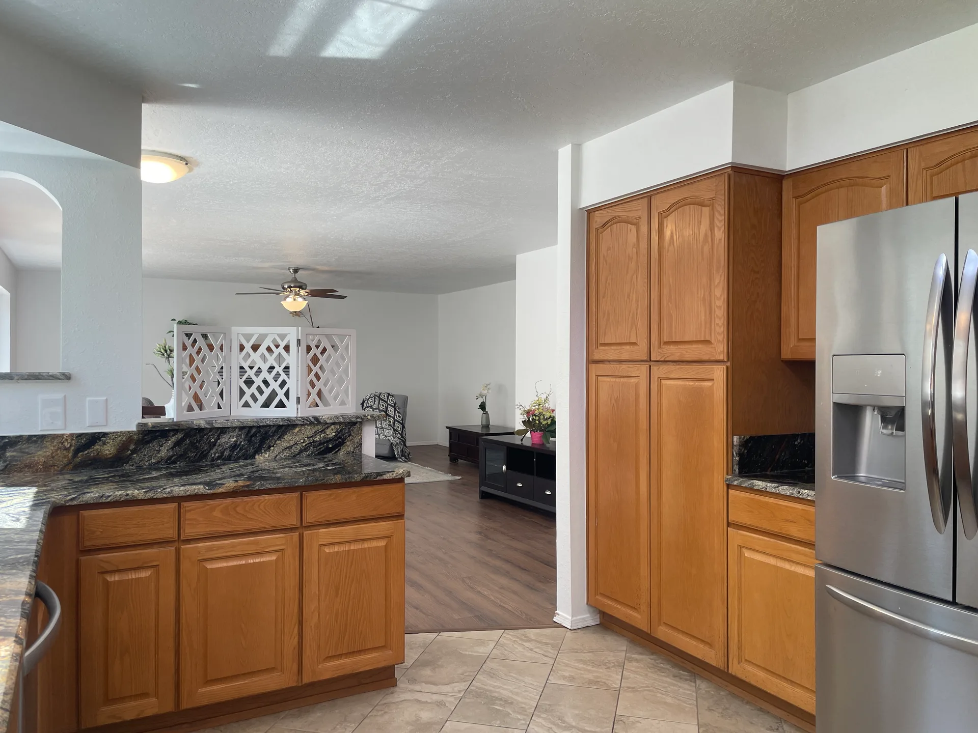 Kitchen view into the living room with oak cabinetry and granite counters