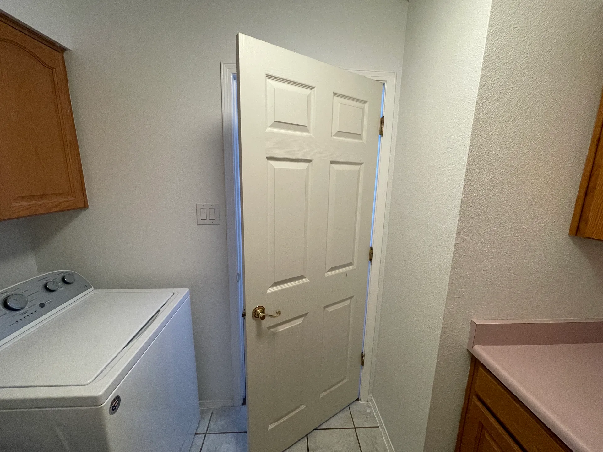 Utility laundry room with cabinetry and a countertop on tiled floors