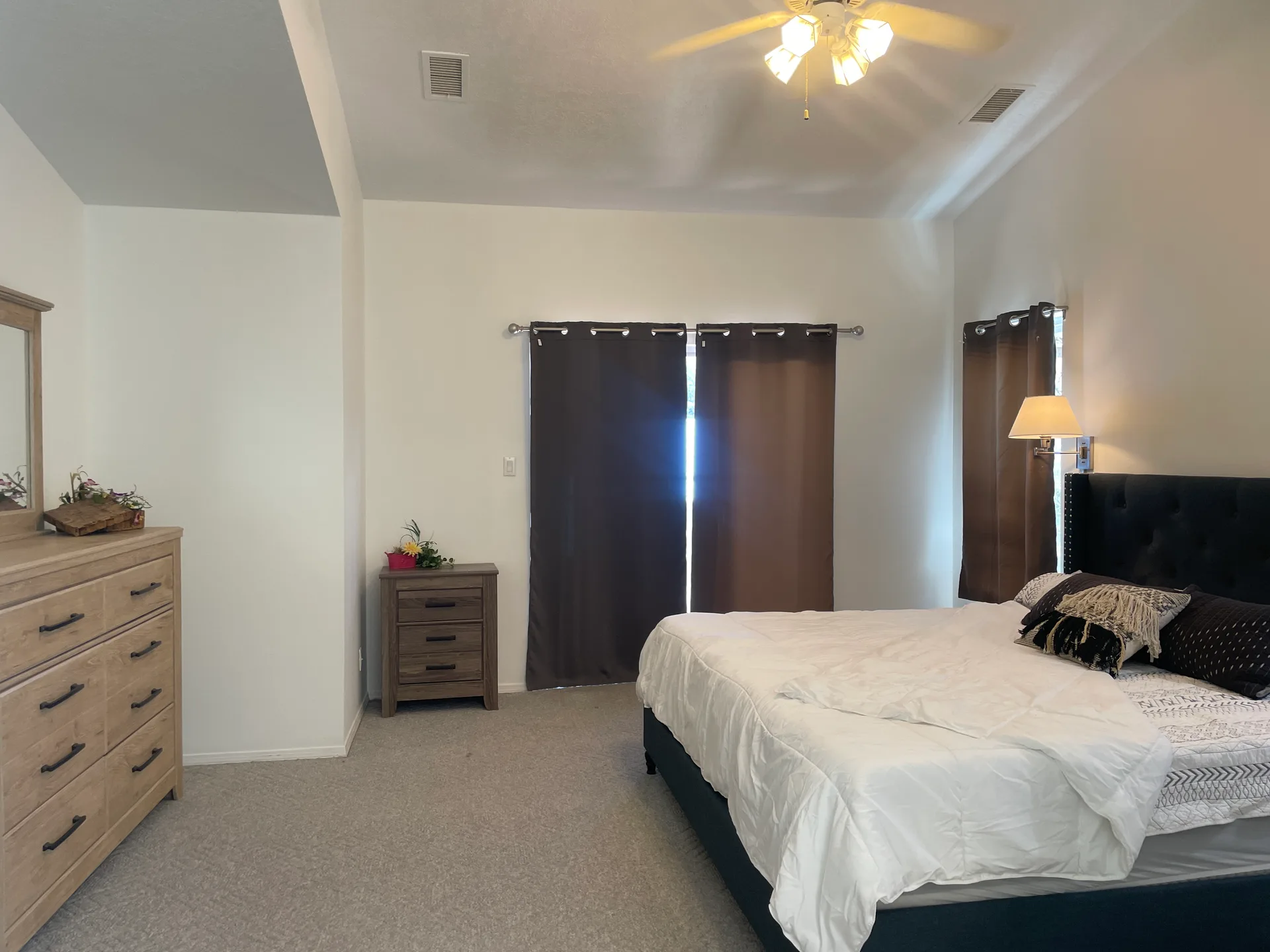 Master bedroom suite with high ceilings, carpeted floors, and neutral walls