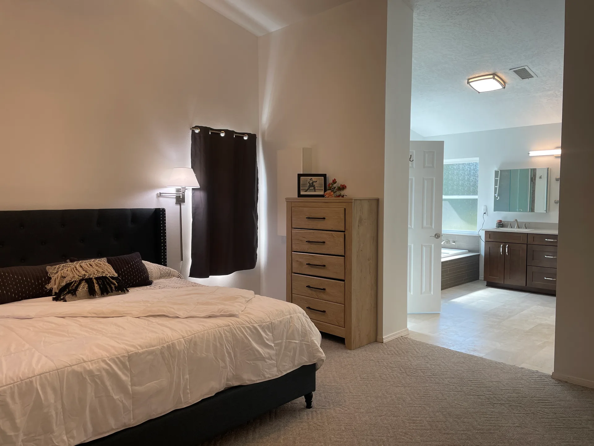 Primary bedroom view into the attached bathroom with vaulted ceilings