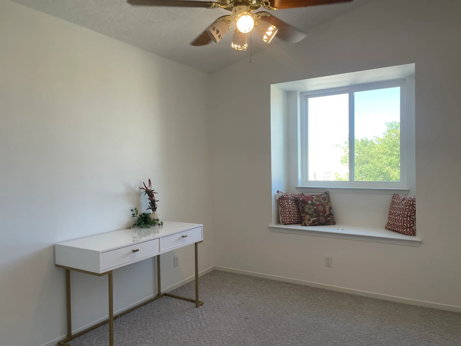 Bedroom with a window seat, white walls, and neutral carpeting