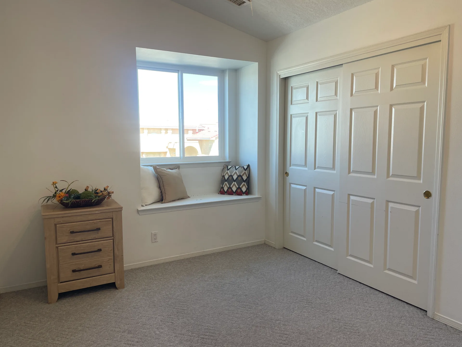 Bedroom interior with window seat, cushions, and neutral decor