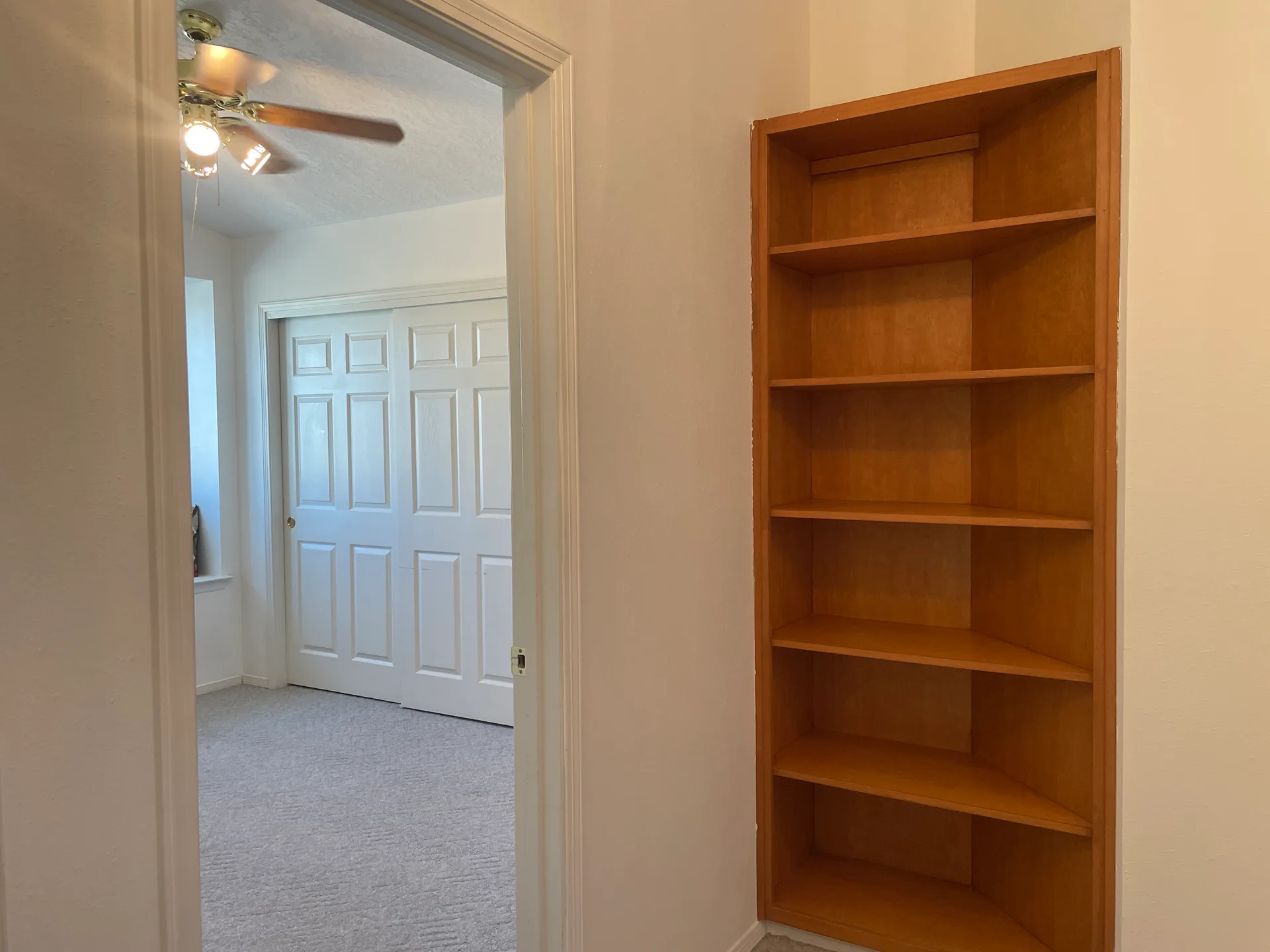 Bedroom doorway view with hallway niche and built-in shelf