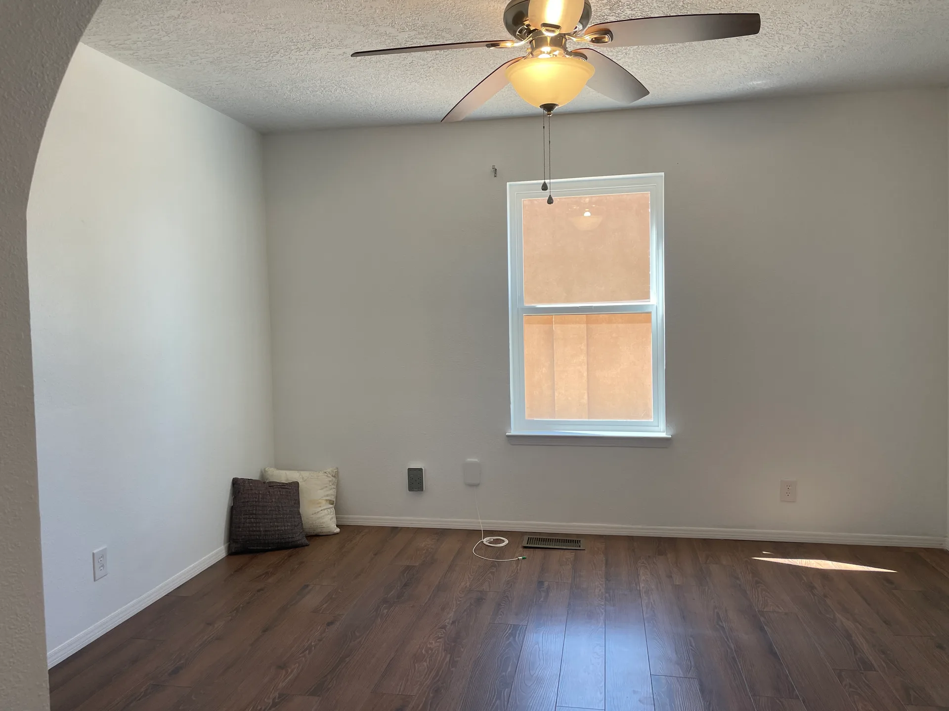 Secondary bedroom with an arched wall entry and wood-look laminate flooring