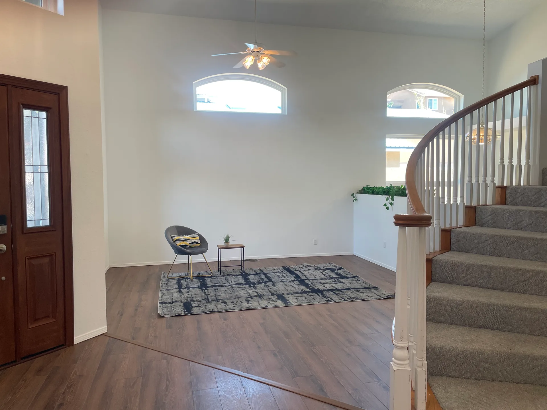 Curved staircase entry foyer with dark wood-style floors and arched windows