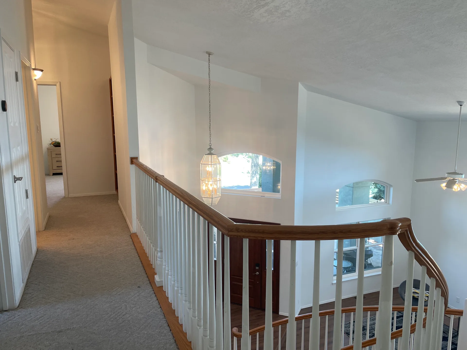 Second-story landing overlooking the foyer with wooden handrail and vaulted ceilings