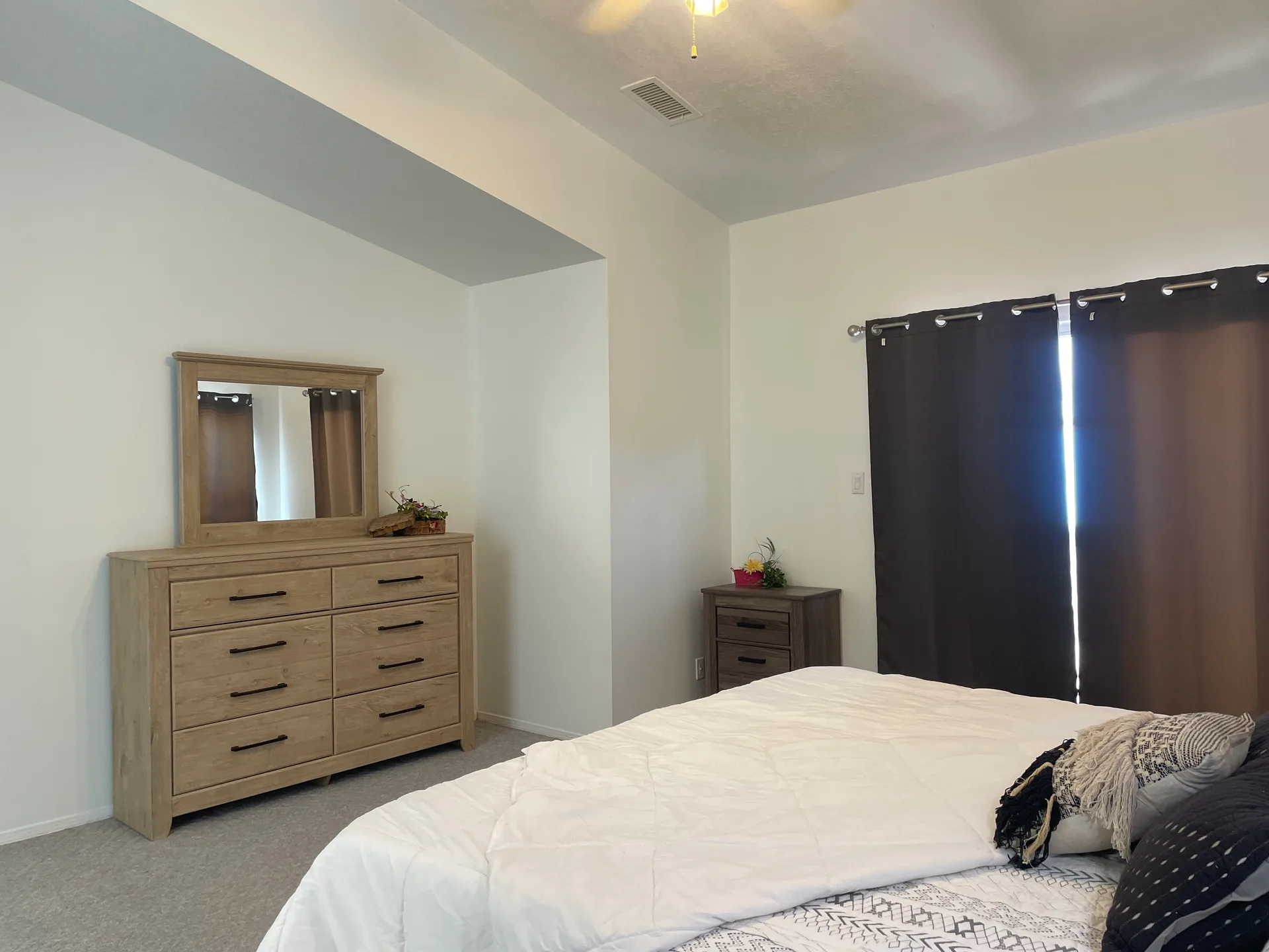 Master bedroom with light wood furniture, gray carpet, and natural daylight