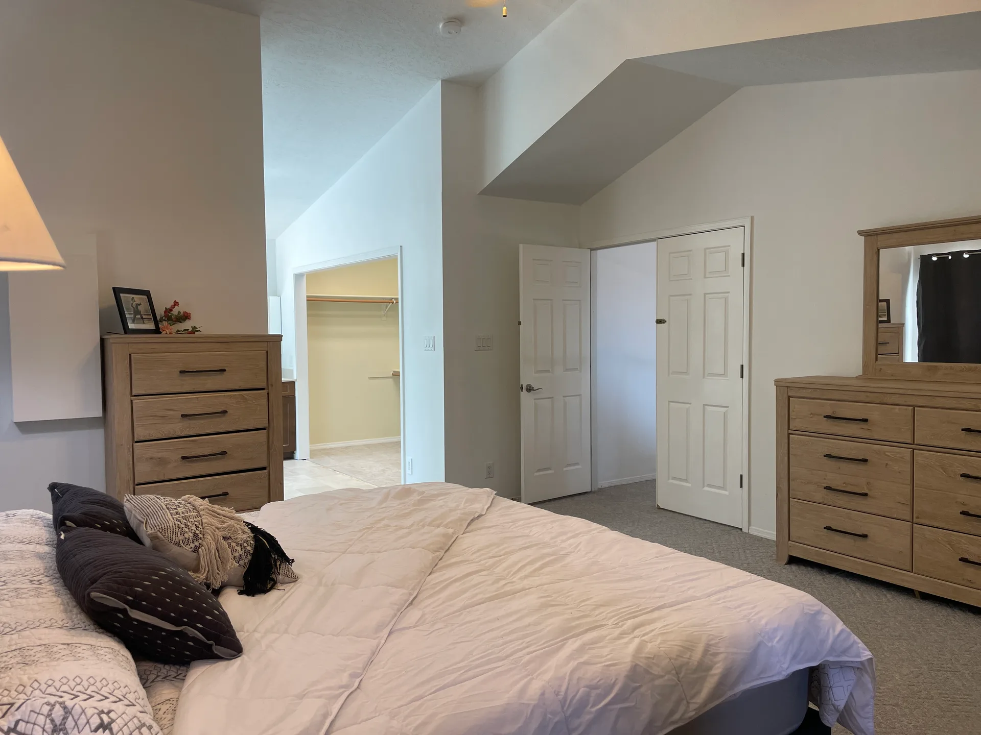 Master bedroom with high vaulted ceilings, beige carpet, and white walls