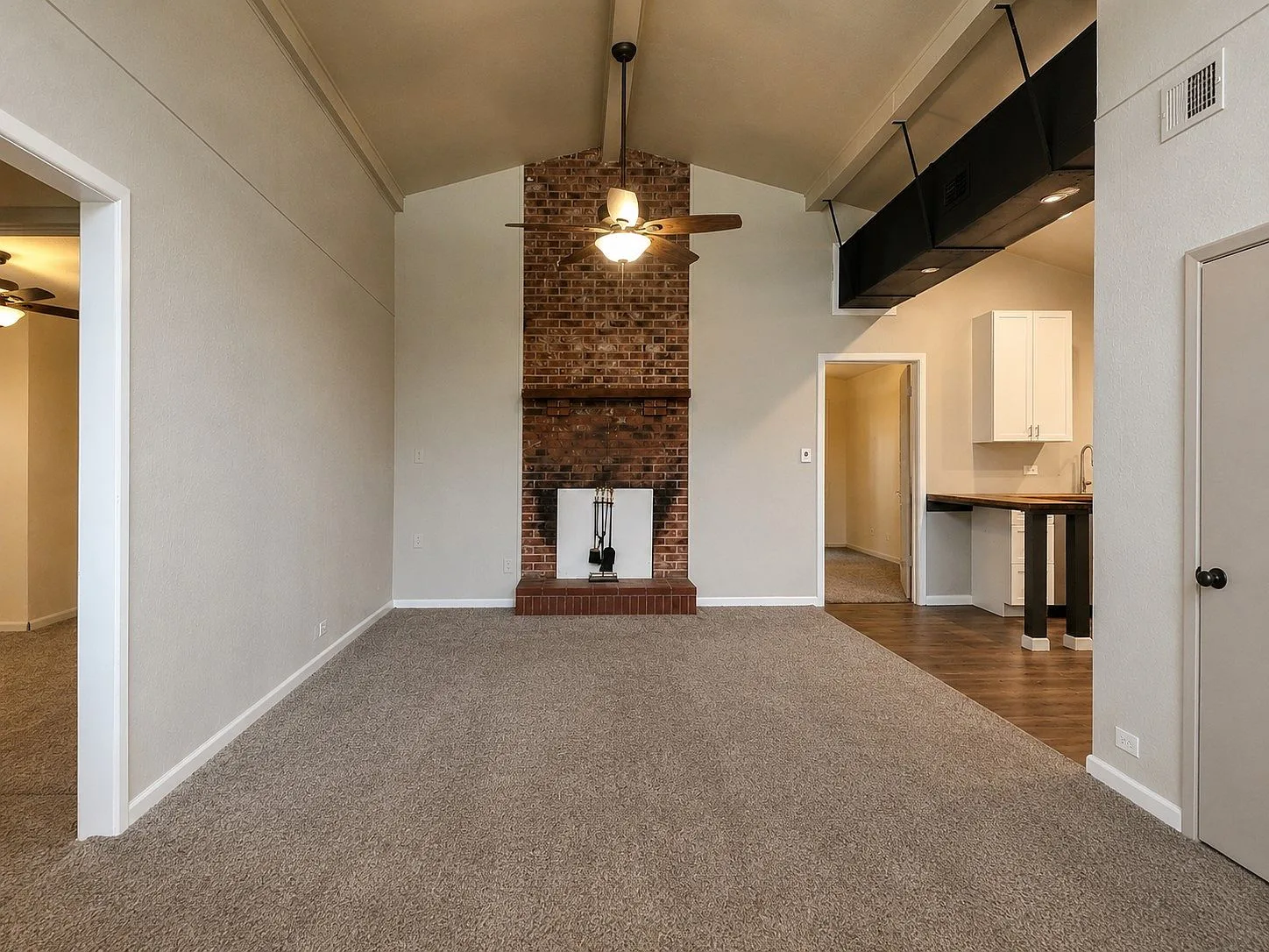 Wide-angle living room with vaulted ceilings and brick fireplace