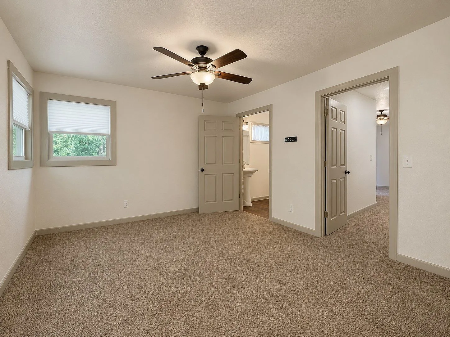 Spacious primary bedroom with neutral tones and natural light