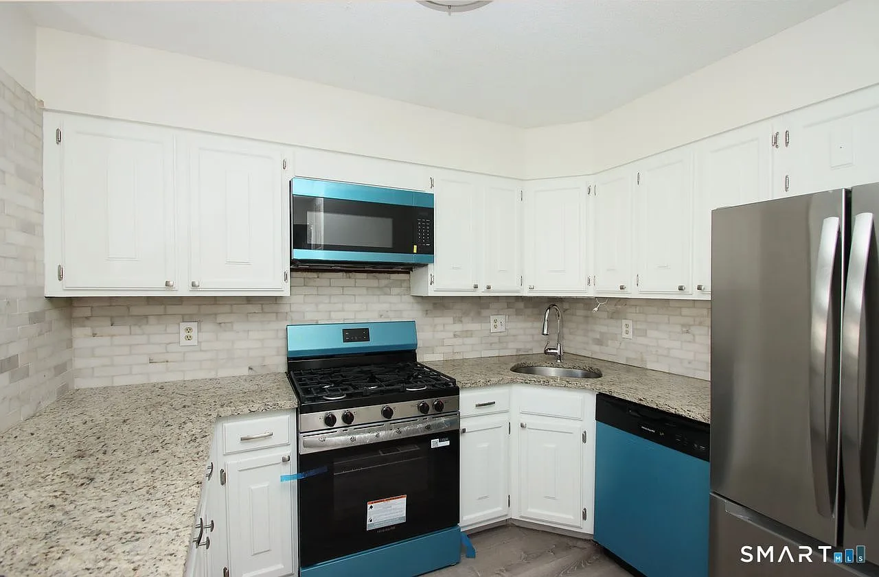 Updated kitchen with white shaker cabinets, granite countertops, and stainless steel appliances