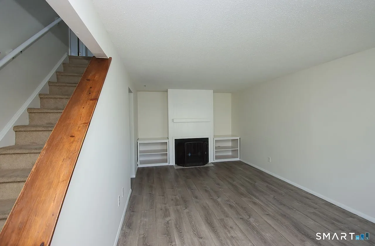 Living room with fireplace, built-in shelving, and grey wood-look flooring