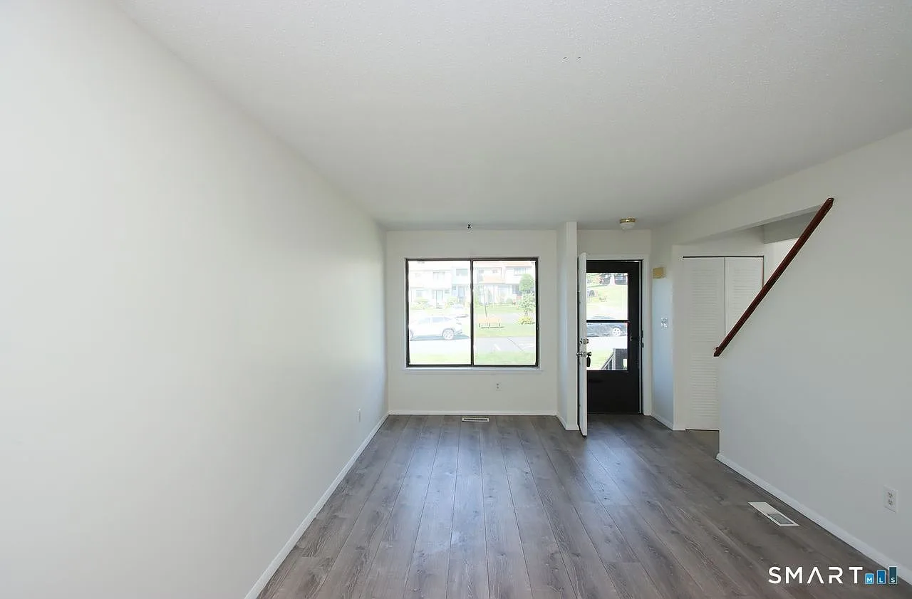 Living room facing the front door and window with staircase handrail