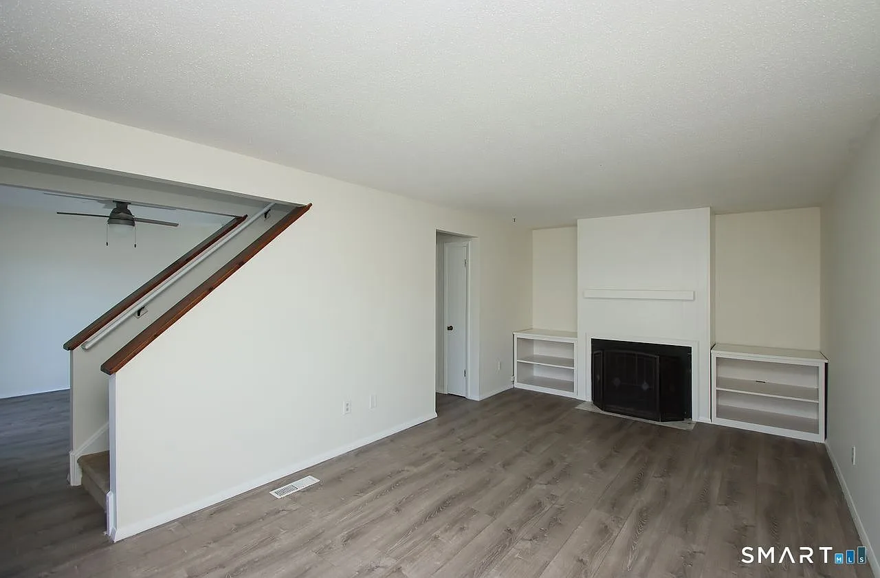 Wide-angle view of living room with fireplace and built-in shelving