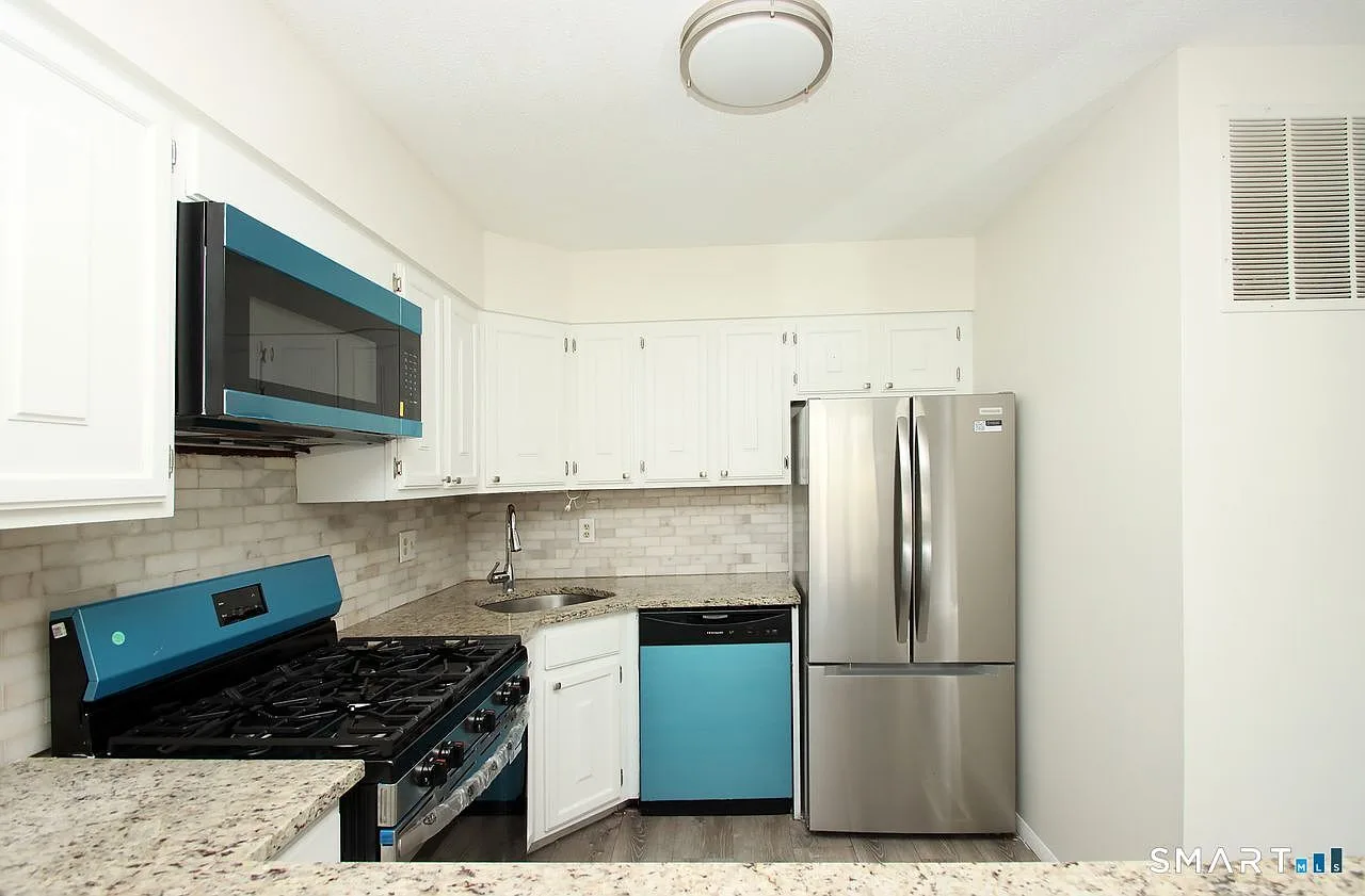 Kitchen with speckled granite countertops and light brick-style backsplash