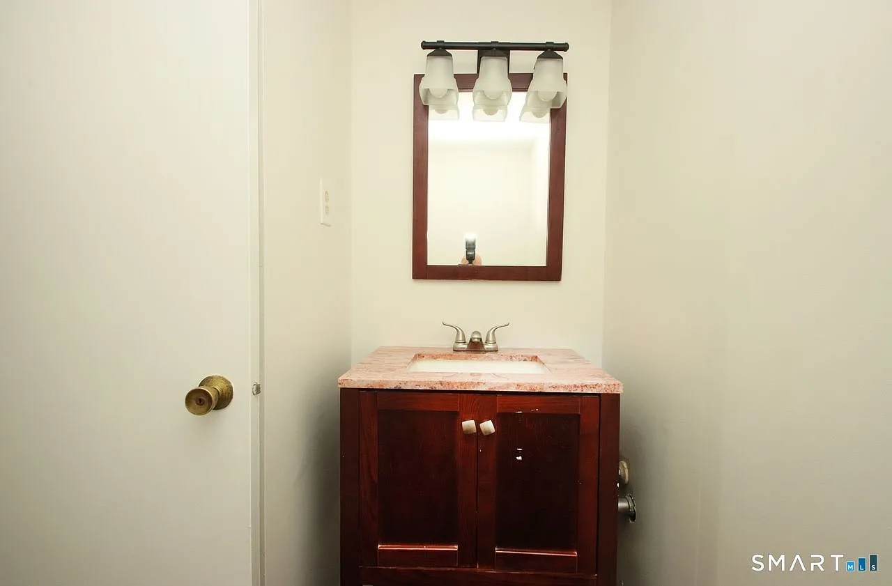 Half bathroom with dark wood vanity and three-light frosted glass fixture
