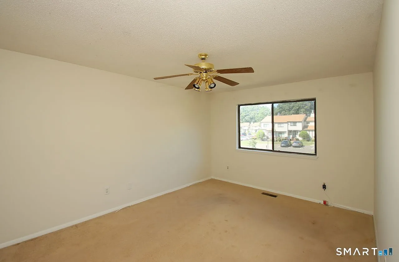 Vacant bedroom with carpeted floors and ceiling fan