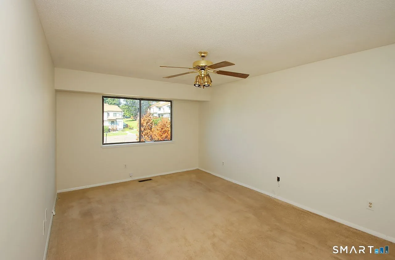 Vacant bedroom with carpeted floors and natural daylight from window