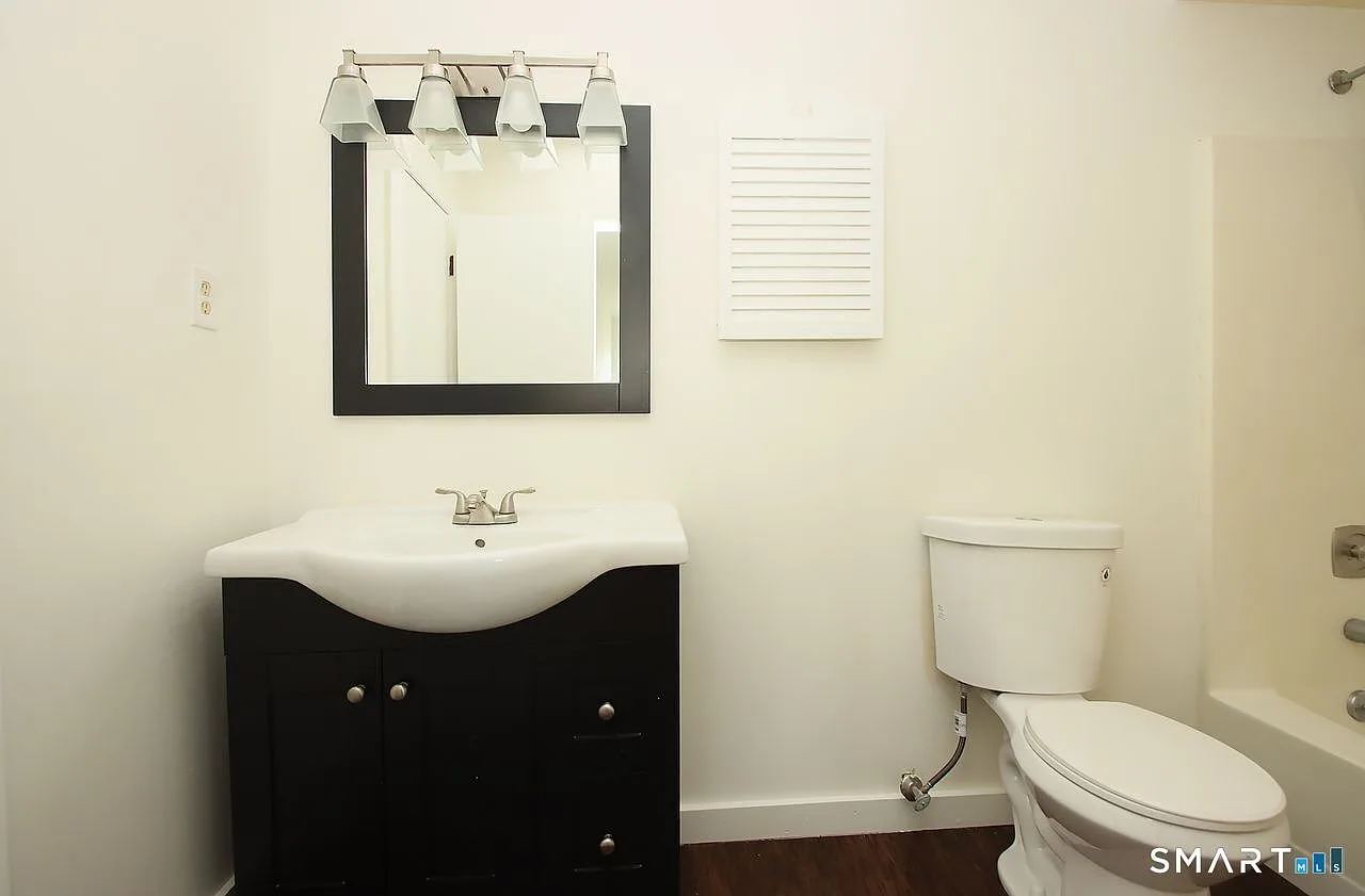 Bathroom with dark wood vanity and wall-mounted mirror