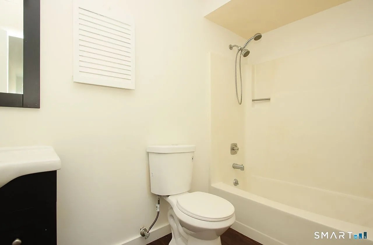 Bathroom with white tub-shower combo and wall-mounted cabinet