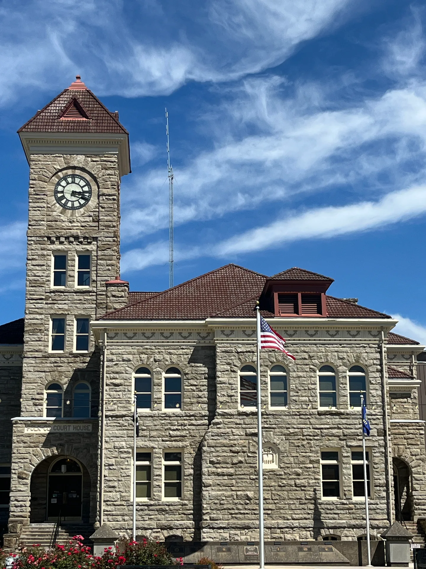 Polk County Courthouse in Dallas, Oregon, a stone building with a clock tower under a bright blue sky