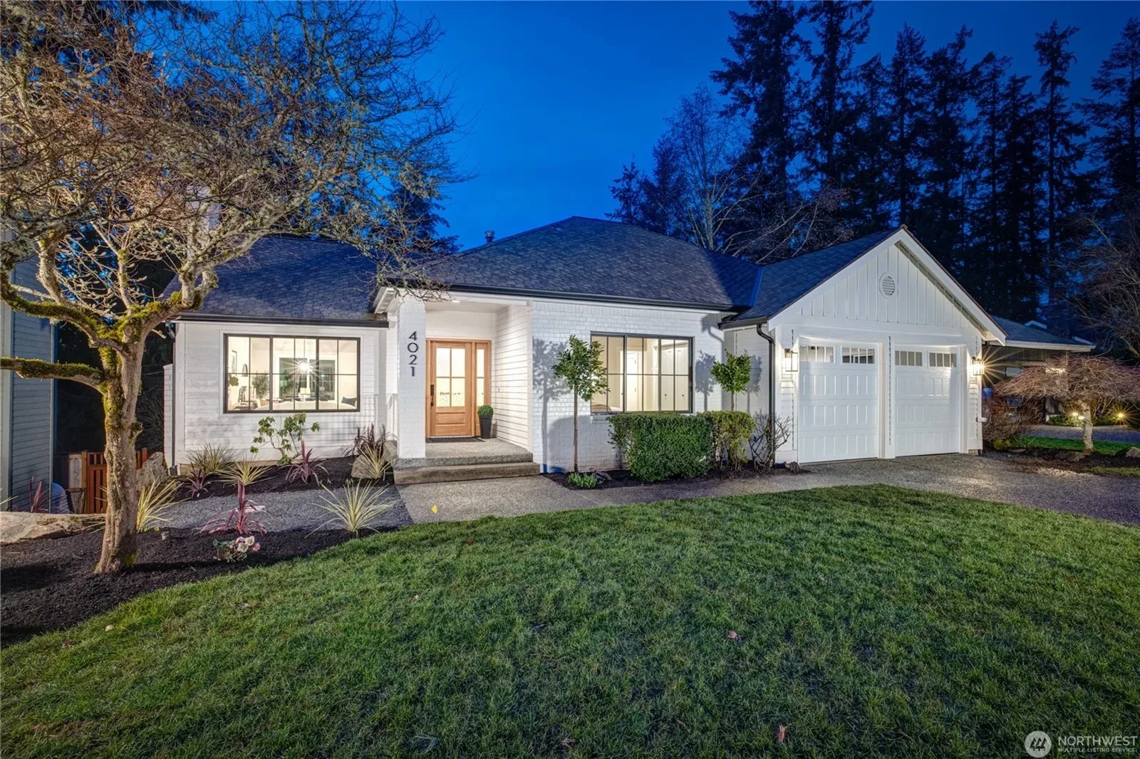 Traditional single-story Sammamish home at dusk with warm interior lighting and exterior sconces illuminated