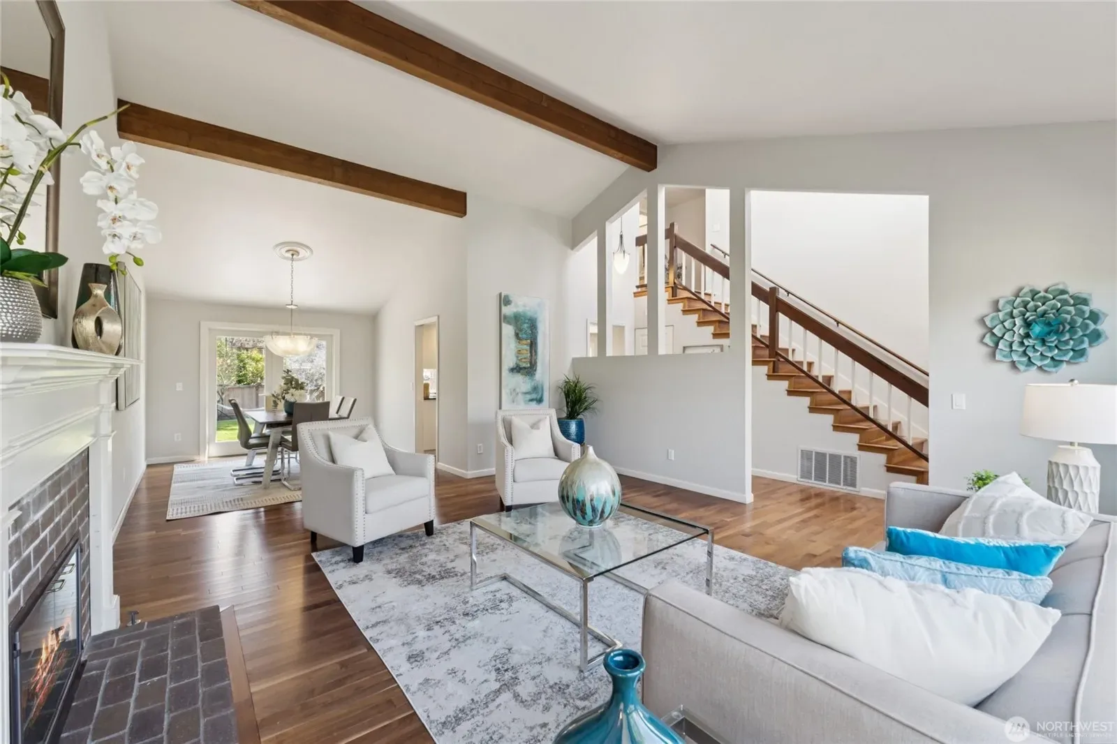 Staged living room with vaulted ceiling, exposed wood beams, and curated neutral decor