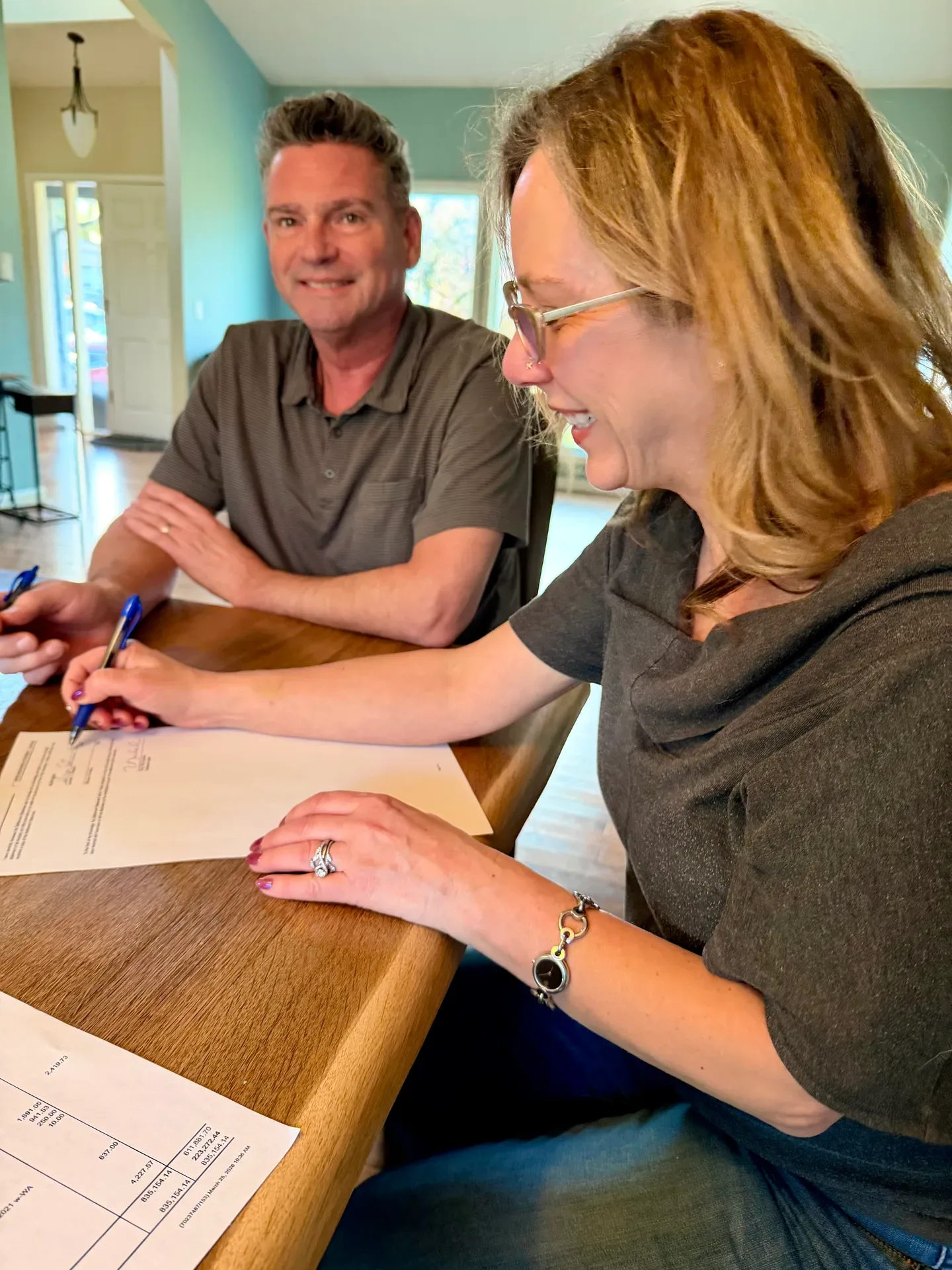 Lynn and Mike sign closing documents at the table, celebrating their successful sale