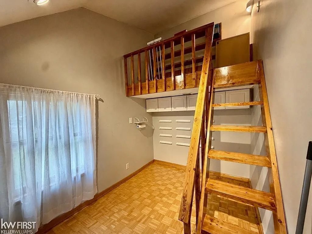 Studio loft area with vaulted ceiling, wooden loft, and neutral walls