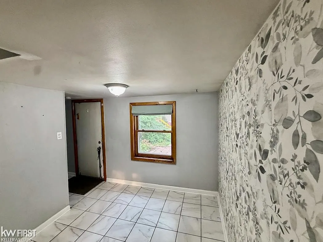 Entryway foyer with tile flooring and monochromatic floral print wallpaper accent