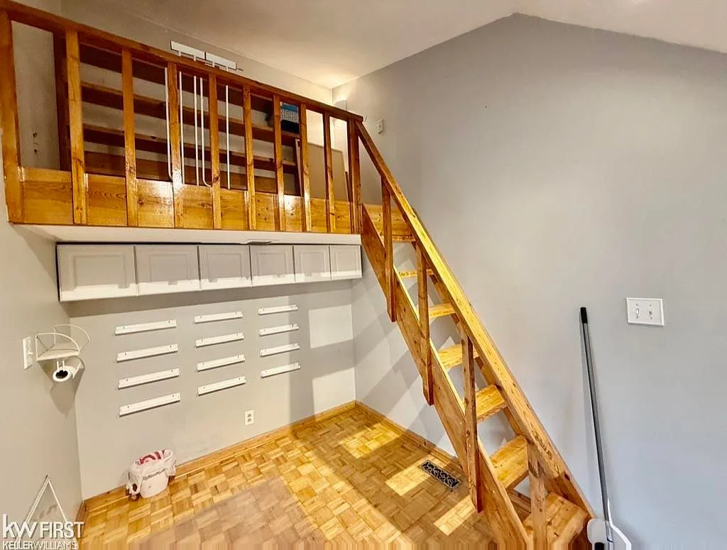 Interior of insulated studio building with wooden staircase to loft and parquet flooring